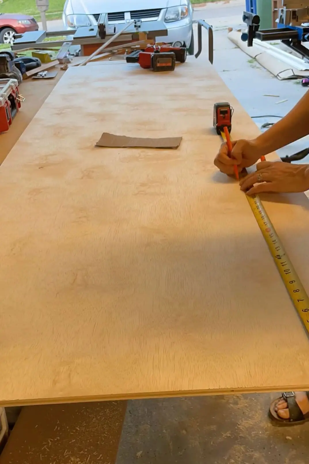 Woman measuring DIY cabinet shelf.